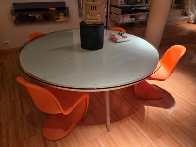 une table blanche avec des chaises orange et une horloge posée dessus