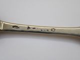 a silver spoon with a handle on a white surface