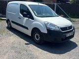 La camionnette blanche est garée sur le chemin de gravier devant une maison.