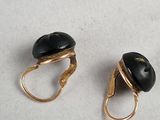pair of gold tone earrings with black stones on them on a white surface