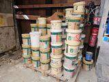 several buckets of paint are stacked on a pallet in a garage