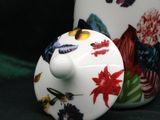 a white vase with a lid that has flowers on it