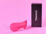 Lunettes de soleil roses Chanel et leur étui sur fond rose