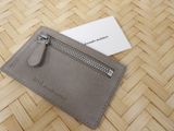 grey leather card holder with zipper and business card on top