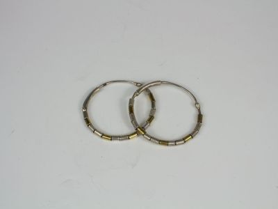 two gold hoop earrings on a white surface