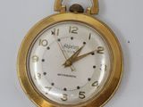a gold pocket watch with a white face on a white surface