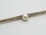 un gros plan sur une broche ornée d'une perle blanche et de diamants