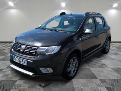 La Dacia noire est garée sur un sol en carrelage à damier.