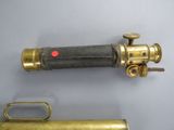 an old brass telescope with a red dot on the side and a brass cylinder on the other side