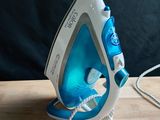 a blue and white steam iron on a wooden table