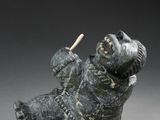 statue of a dog holding a baseball bat on a gray surface
