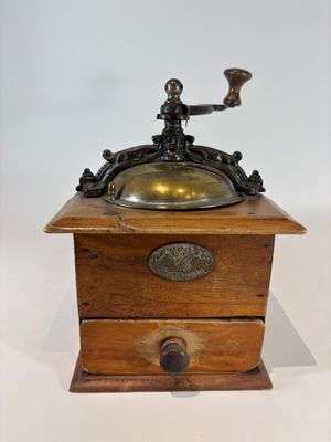 an old fashioned coffee grinder with a brass plate on top of it
