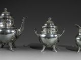 trois théières en argent et une cafetière posées sur une table