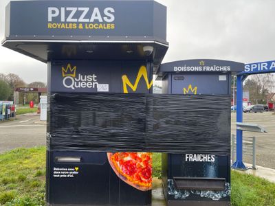 un stand de pizza avec une pizza dessus, dans un parking