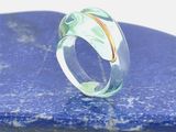 une bague transparente ornée d'un anneau en or serti d'une pierre bleue
