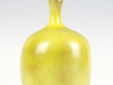 un vase jaune posé sur une table blanche