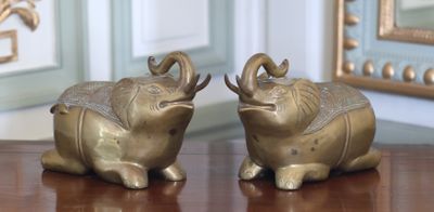 deux éléphants assis sur une table en bois, avec un miroir en arrière-plan