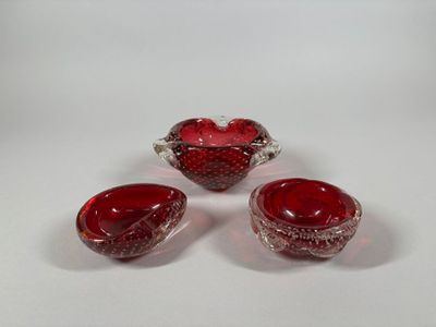 three red glass bowls and a bowl on a white surface