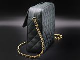 a black purse with a gold chain on a black background