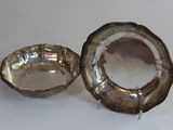 two silver plated dishes on a white surface with a mirror in the background