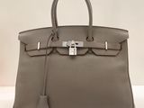un sac à main en cuir gris posé sur une table blanche