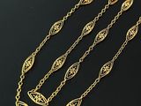 a gold necklace with three chains and a pendant with a leaf design