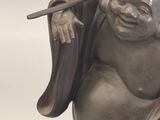 a statue of a laughing buddha holding a stick