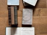 plusieurs vieux livres posés sur un plancher en bois, dont l'un est ouvert et l'autre fermé