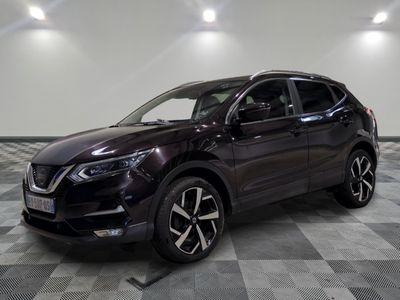 un SUV Nissan de couleur foncée garé sur un sol à damier