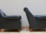 pair of black leather armchairs with studded arms and arms