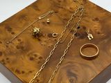 wooden jewelry box with gold rings and chains on a white background