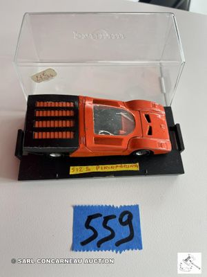 une petite voiture miniature dans une boîte transparente posée sur une table