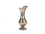 un vase en argent posé sur une surface blanche