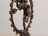 bronze statue of a man playing a flute on a table