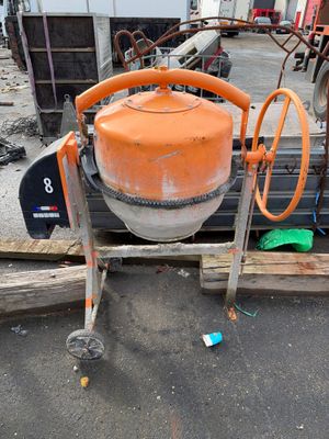 une bétonnière de couleur orange posée sur une palette dans une cour