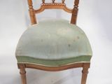 an old wooden chair with a green upholstered seat