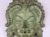 une sculpture verte représentant un visage sur le mur