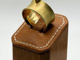 a gold ring with a diamond sitting on top of a wooden block