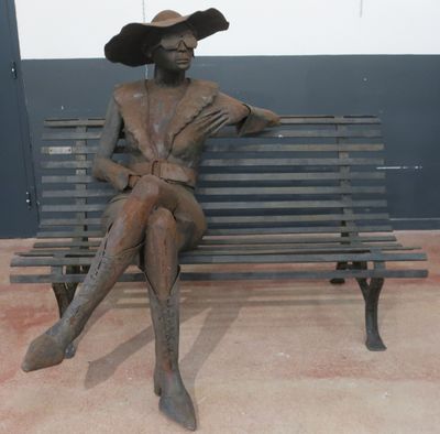 a bronze statue of a woman sitting on a bench
