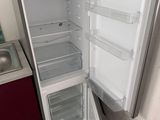 a refrigerator with its door open and a sink in the corner