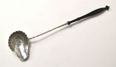 une cuillère en argent avec un manche noir posée sur une surface blanche