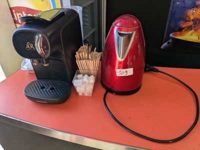 une cafetière rouge posée sur un plan de travail, à côté d'une tasse de café