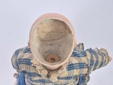 a small doll sitting on the ground with a hat on it ' s head