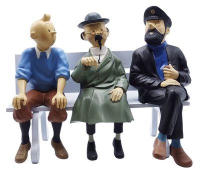 trois figurines représentant des personnes assises sur un banc