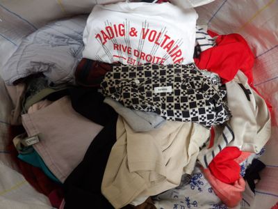 un tas de vêtements dans un panier posé sur un lit