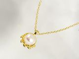 a gold necklace with a white pearl on a gold chain