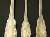 three silver spoons and a fork on a black surface