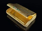 an image of a gold cigarette case on a black surface