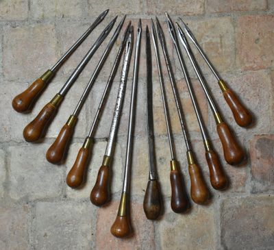 un ensemble de huit ciseaux en bois et en métal sur un mur de briques