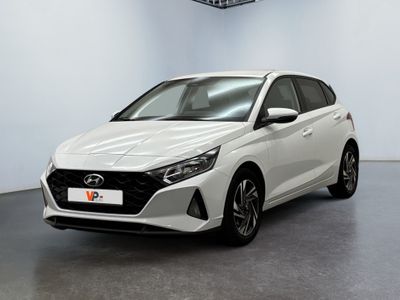 Une voiture blanche est garée dans une pièce équipée d'un ventilateur de plafond.